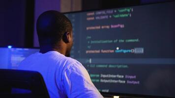 African American hacker coding a cyber attack in dark office video