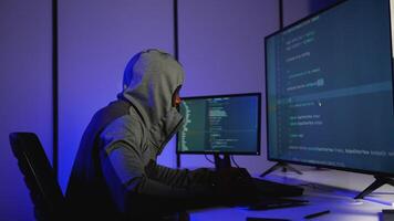 Anonymous hacker in hoodie coding cyber attack in dark room video