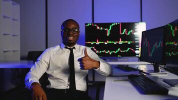 Successful trader giving thumbs up in front of stock charts video