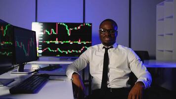 Confident trader smiling in front of stock market charts video