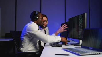Two IT specialists analyzing data on multiple monitors video