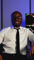 Confident trader smiling in front of stock market charts video