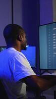 African American programmer coding on multiple screens at night video