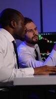 Two investment fund analysts analyze stock market charts on multiple monitors in office video