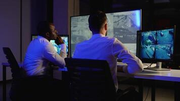 Two security guards monitoring CCTV footage in control room video