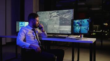 Security guard monitoring CCTV and talking on radio video