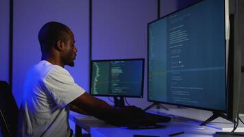 Focused programmer coding on multiple screens at night video