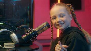 Caucasian little teen girl daughter child kid streamer gamer influencer gen z internet game computer addiction at night radio stream showing pointing index finger at camera smiling hey you look photo