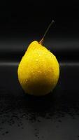 one wet pear on the table, a delicious yellow pear covered with water photo