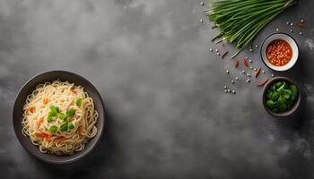 Plain instant noodles with chive garnish on mottled grey surface. Flat lay, top view with copy space photo