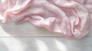Soft pink fabric draped elegantly over white wooden surface in sunlight photo