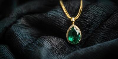 Elegant gold necklace with emerald pendant on luxurious black fabric photo