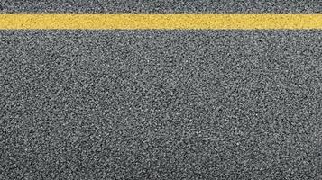 Close-up view of asphalt road surface with yellow line for transportation concept photo