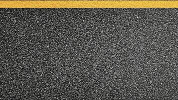 Close-up of textured asphalt road with yellow line dividing surface for transportation concept photo