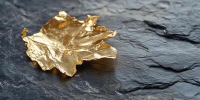 Golden leaf on dark slate background symbolizing elegance and luxury photo