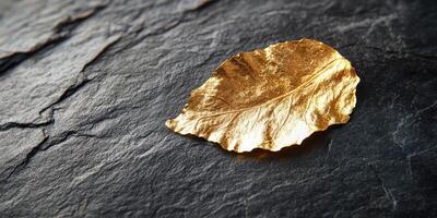 Golden leaf on dark slate surface reflecting elegance and luxury concept photo