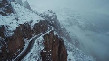 Snow-covered mountain road winding through majestic cliffside in winter landscape photo