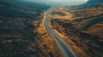 Winding rural road through arid landscape in golden hour light with mountain background photo