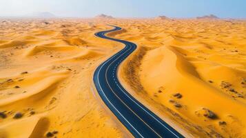 Winding road through vast golden desert dunes in sunlit landscape photo
