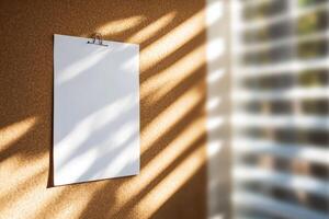 Blank white paper hanging on a textured wall with sunlight patterns photo