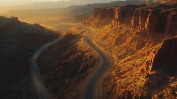 Winding road through desert canyon landscape at sunset with rugged terrain photo