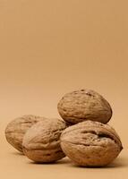 Stack of walnut fruits on brown background, close up photo