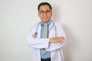 A man in a white lab coat is smiling and holding a stethoscope. Concept of professionalism and confidence, as the man is posing for a picture while wearing his medical attire photo