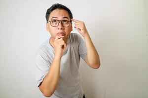 A young man pointing to his forehead, expressing deep thought or concentration, against a plain background. photo