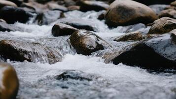 A stream of water flows over a rocky riverbed. The water is clear and cold, and the rocks are large and jagged. The scene is peaceful and serene, with the sound of the water photo