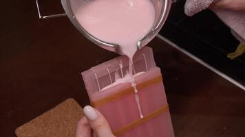 Fresh, warm, pink wax is carefully poured into specially designed mold to create candles at home. wax is allowed to set and cool, giving it perfect shape for each candle. video
