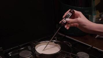 When cooking milk, butter, cream, or white chocolate at home, cook measures desired temperature using thermometer to ensure that food is cooked to right consistency. video