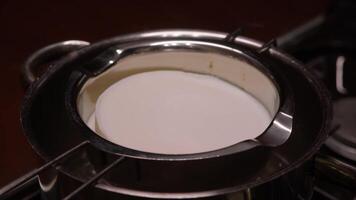 timelapse of the process of melting piece of white wax in saucepan in water bath to create a candle at home. cook melts white chocolate video