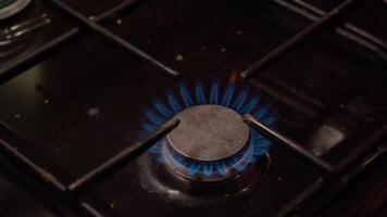 A bright blue natural gas flame burns steadily on the stove, while a dirty black gas stove is switched on. Close up. video