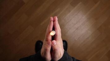 Man praying with candle in hands, top view, pov video