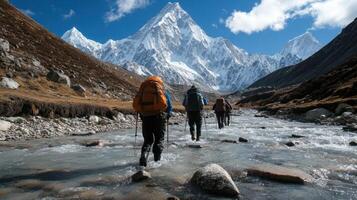 Hikers trekking through a river with mountains in the background. photo