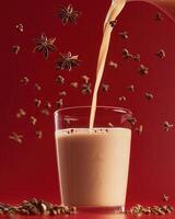 A glass of spiced tea being poured, with star anise and cloves floating around photo