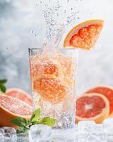 A refreshing drink with grapefruit slices splashing in a glass, surrounded by ice and fruit. photo