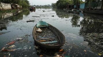 A polluted waterway with a discarded boat amidst floating debris and waste. photo