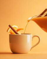 A warm beverage being poured into a cup, garnished with orange slices and cinnamon sticks. photo