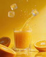 A refreshing orange drink splashes in a glass with ice cubes, surrounded by fresh oranges. photo