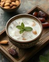 A bowl of yogurt with ice, nuts, and dates, garnished with mint leaves. photo