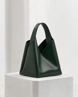 A minimalist green handbag displayed on a pedestal, showcasing modern design. photo