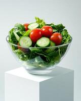 A fresh salad in a glass bowl, showcasing vibrant greens and ripe tomatoes. photo