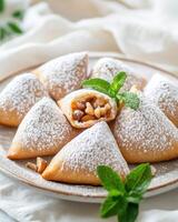 A plate of triangular pastries dusted with powdered sugar, revealing a nut filling photo