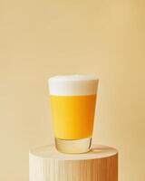 A glass of yellow beverage with foam on a wooden pedestal against a soft background. photo