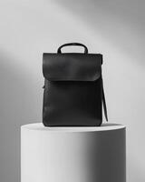A sleek black backpack displayed on a pedestal with soft lighting. photo