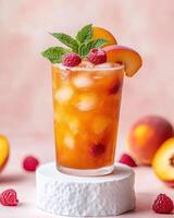 A refreshing peach and raspberry drink garnished with mint, served on a textured pedestal photo