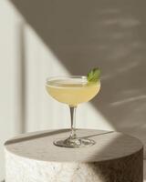 A refreshing cocktail garnished with a mint leaf, elegantly displayed on a marble surface. photo