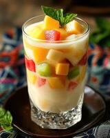 A refreshing dessert featuring colorful fruit cubes in a creamy base, garnished with mint. photo
