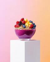 A vibrant smoothie bowl topped with fruits and granola, served in a glass bowl. photo